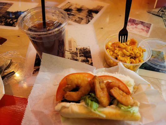 Shrimp Po'Boy (half eaten) w/ Mac and Cheese and lemonade Iced tea.