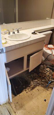 underground pipe leak, below a bathroom cabinet.