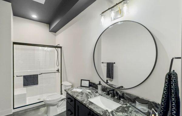 Sliding Shower Door, Round Vanity Mirror, and Bathroom Accessories in Matte Black