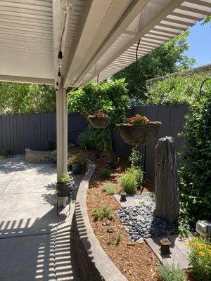 Existing hanging baskets and existing water feature are completed by new trellises and plants