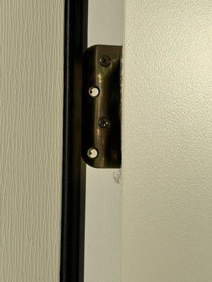 Example of missing screws on a door hinge.