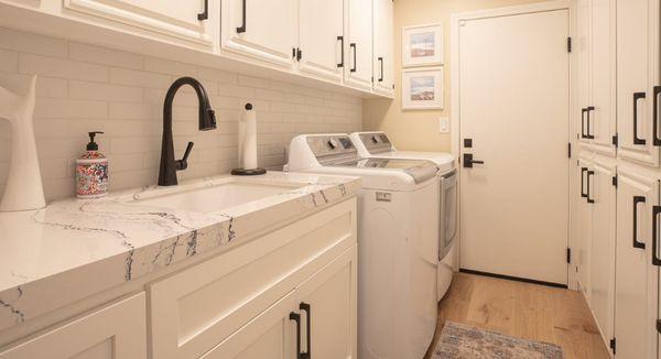 This Laundry Room Features Shaker White Cabinetry and Marble Printed Quartz Countertops