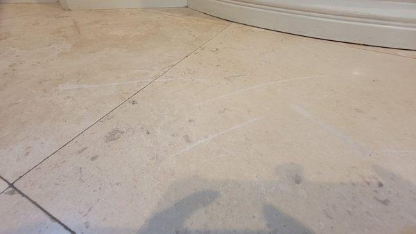 5 deep scratches on two travertine tiles caused by a fumigation metal fan.