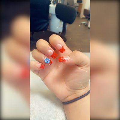 Red French tip Acrylic Nails with a blue rose jewelry.