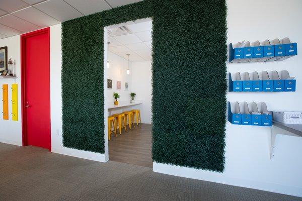 Cafeteria entrance wrapped by wall greenery, with blue mailboxes for team members.