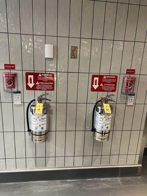 New installed K-Class Fire Extinguishers 
next to the emergency push station of the kitchen hood fire suppression system