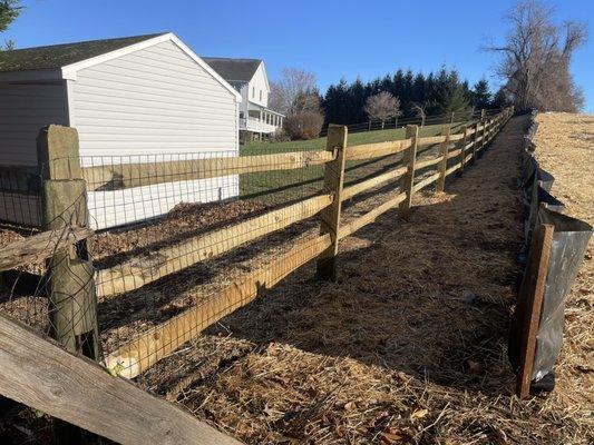 Pressure treated pine 3 rail split rail fence with black pvc coated wire.