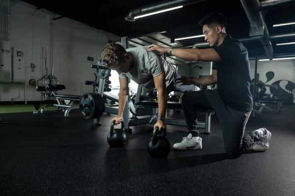 Coach Josh guiding Nate through a decline elevated push-up--an advanced exercise demanding coordination and upper body strength.