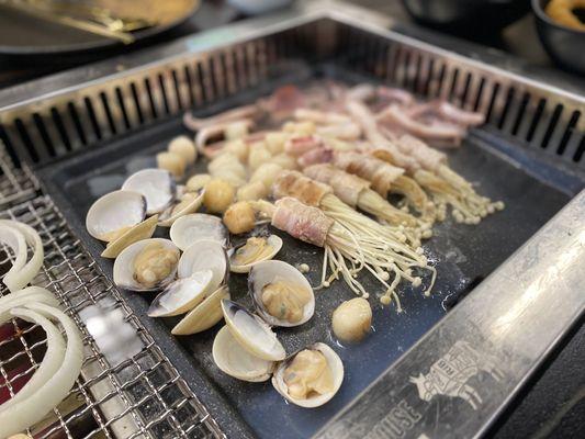 Clams, scallops, and enoki mushrooms wrapped with bacon.