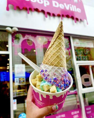 Medium size cotton candy cheesecake ice cream topped with more cheesecake bites topped with a cotton candy dust cone