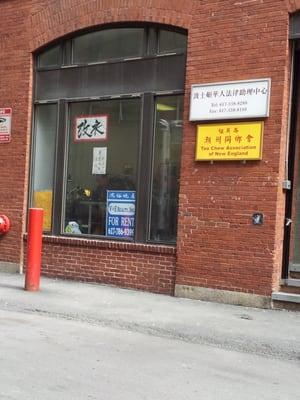 Storefront of Cai Sheng Tailoring. Mr. Cai is seen working at his sewing machine.