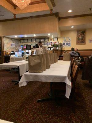 Assembly line of paper bags for orders to go in the center of the restaurant mostly for food delivery services.