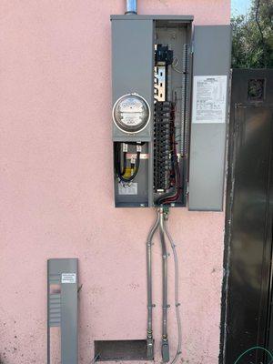 Open electrical panel on pink stucco wall. Reliable circuit breaker and wiring installations!