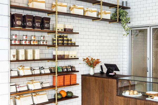 Brass and Walnut shelves against subway tile wall, with Walnut counter and glass display case at the new Valerie Confections in Glendale.