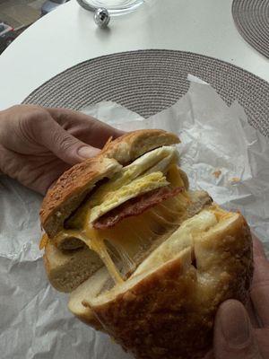 Breakfast bagel with melted cheddar, sausage, bacon in a Parmesan bagel