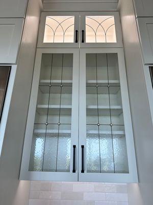 Traditional style decorative glass inserts for double height cabinet doors using textured glass and black metal finish