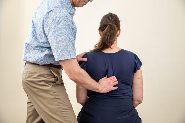 Dr Elon Bartlett examining a patient's back.