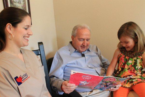 Caring Senior Service caregiver reading with a client and his granddaughter