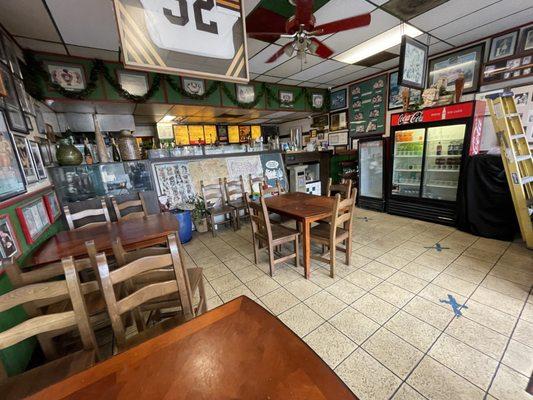 Dining area, including a half-full beverage refrigerator and stuff stored in the corner.