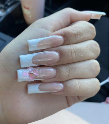 White french tip nails with a flower on the ring fingers