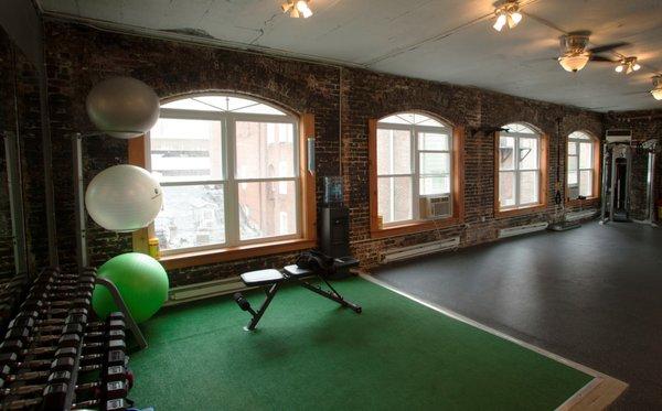 Front half of our spacious studio. Dumbbells, benches, turf, cables, and space.