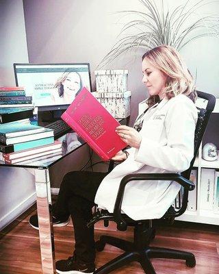 The best implant specialist in Aventura keeping up with her studies.