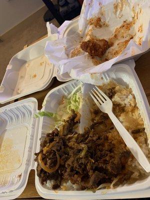 Half eaten spicy beef teriyaki with almost finished container of Korean fried chicken in back.