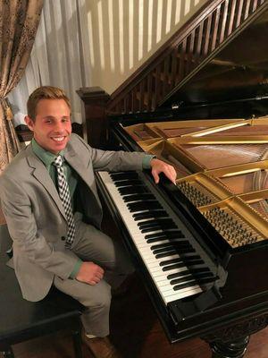 Ryan Newbauer sitting at the Piano Lessons 123 studio piano, a Heintzman grand from the year 1900.