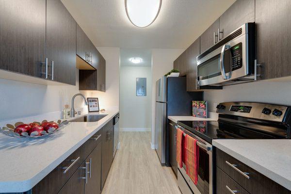 Modern kitchen with dark cabinetry, white granite countertops and stainless steel appliances.