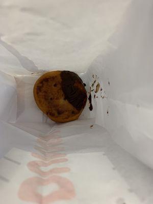 Sad Boston crème donut with only half the donut coated in chocolate