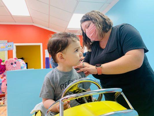 Receptionist dusting him off and getting him ready for his first-haircut "after" photo.