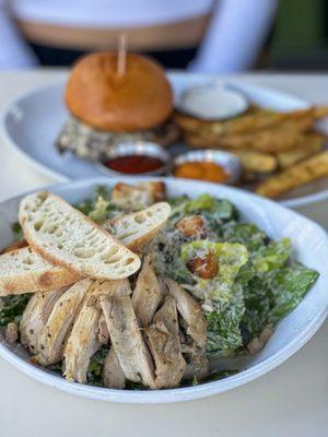 caesar salad with chicken, wagyu burger in the back