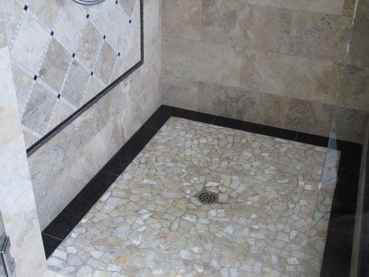 Shower with combination of onyx basin, silver Travertine, and center piece design on wall.