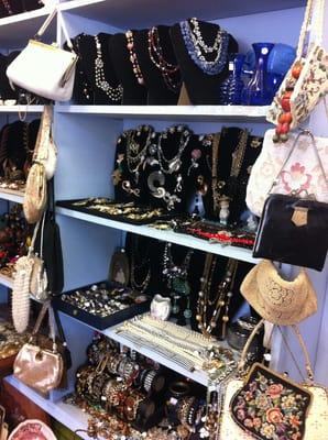 The shelves are lined with vintage jewelry and handbags from the 20s to the 80s.