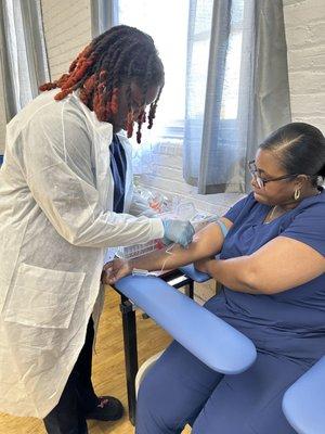 Cmedtraining phlebotomist student drawing blood using a butterfly needle.