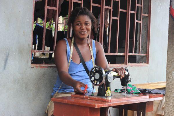 vocational tailoring graduate with donated sewing machine / toolkit