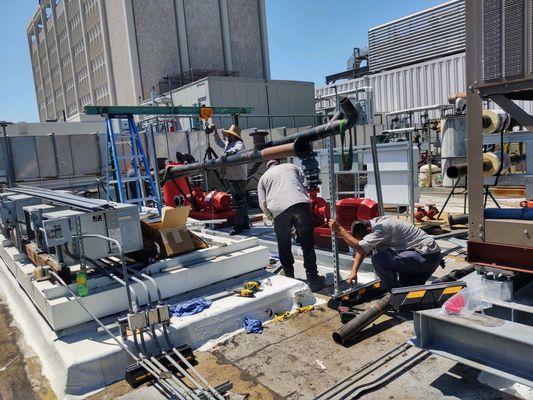 Nelly, Simpson, & Marco are hard at work in the sun, Chiller water  Piping assembly on the roof.