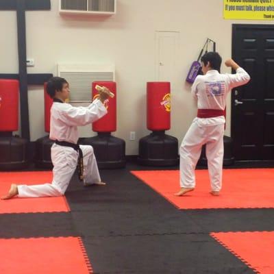 Master Tuananh holding the board for Alikhan's black belt promotion.