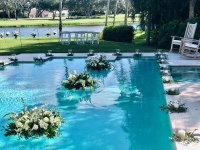 Love how we took the small greenery wreaths and used them around the glass hurricane candles to make this back yard wedding beautiful!