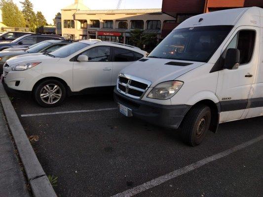 Van clearly parked 4+ feet from curb side in front parking lot