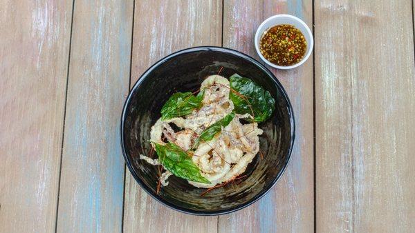 Crispy Calamari, battered in rice flour, served with a citrus chili dressing, pickled fresno and basil