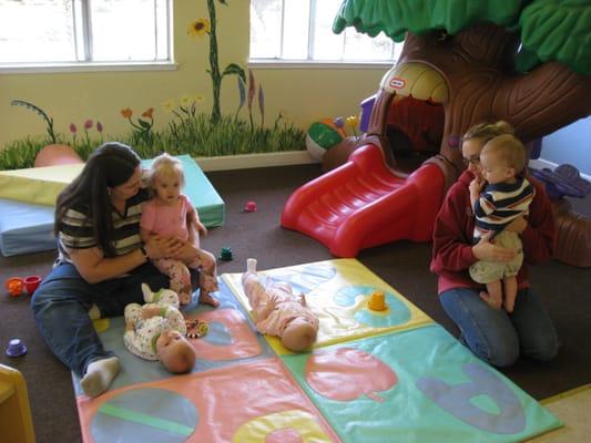 The infant room at Bert & Ernies has a padded floor and a mini tree house with a silde. An outdoor area has grass and and toys.