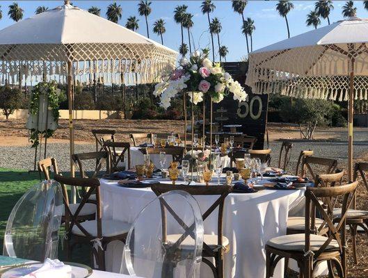 Fringe umbrellas, round tables, linens, crossback chairs and glassware setup in Los Angeles. Visit our website at www.fiestakingrental.com