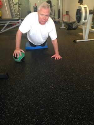 Bill showing how to do a one arm push up using a small medicine ball.