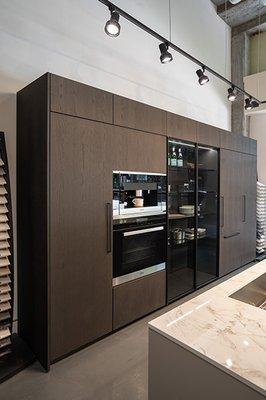 Pedini oak veneer tall cabinet units, countertop Dekton in Bergen Stonika, Miele appliances