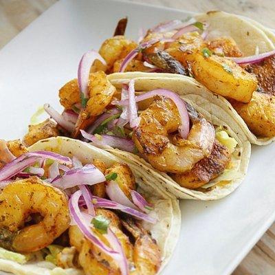 Peruvian tacos fusion, fish and shrimp marinaded in anticuchera sauce top with criolla