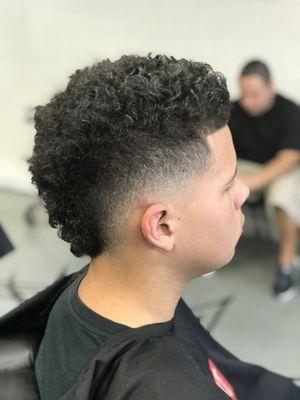 Skin fade Mohawk with curly top.