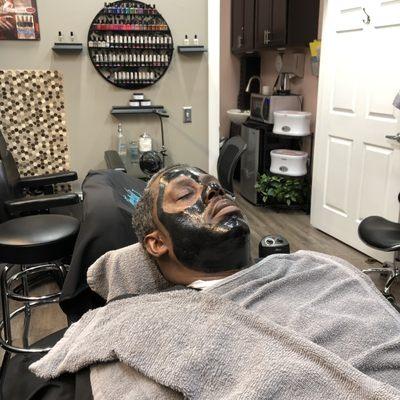 Black mask applied to client facial area to remove grime & dirt.