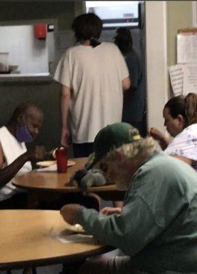 Same resident inside kitchen handing food to other residents