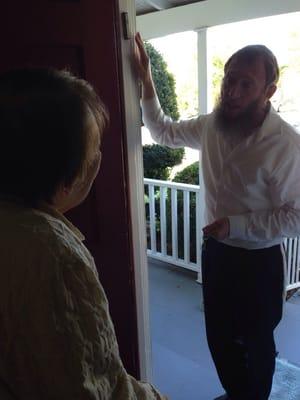 Rabbi Yoske places a brand new Kosher mezzuzah on a friend's door